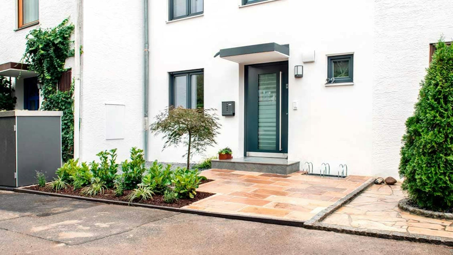 Vorgarten mit Natursteinplatten und immergrünen Pflanzen