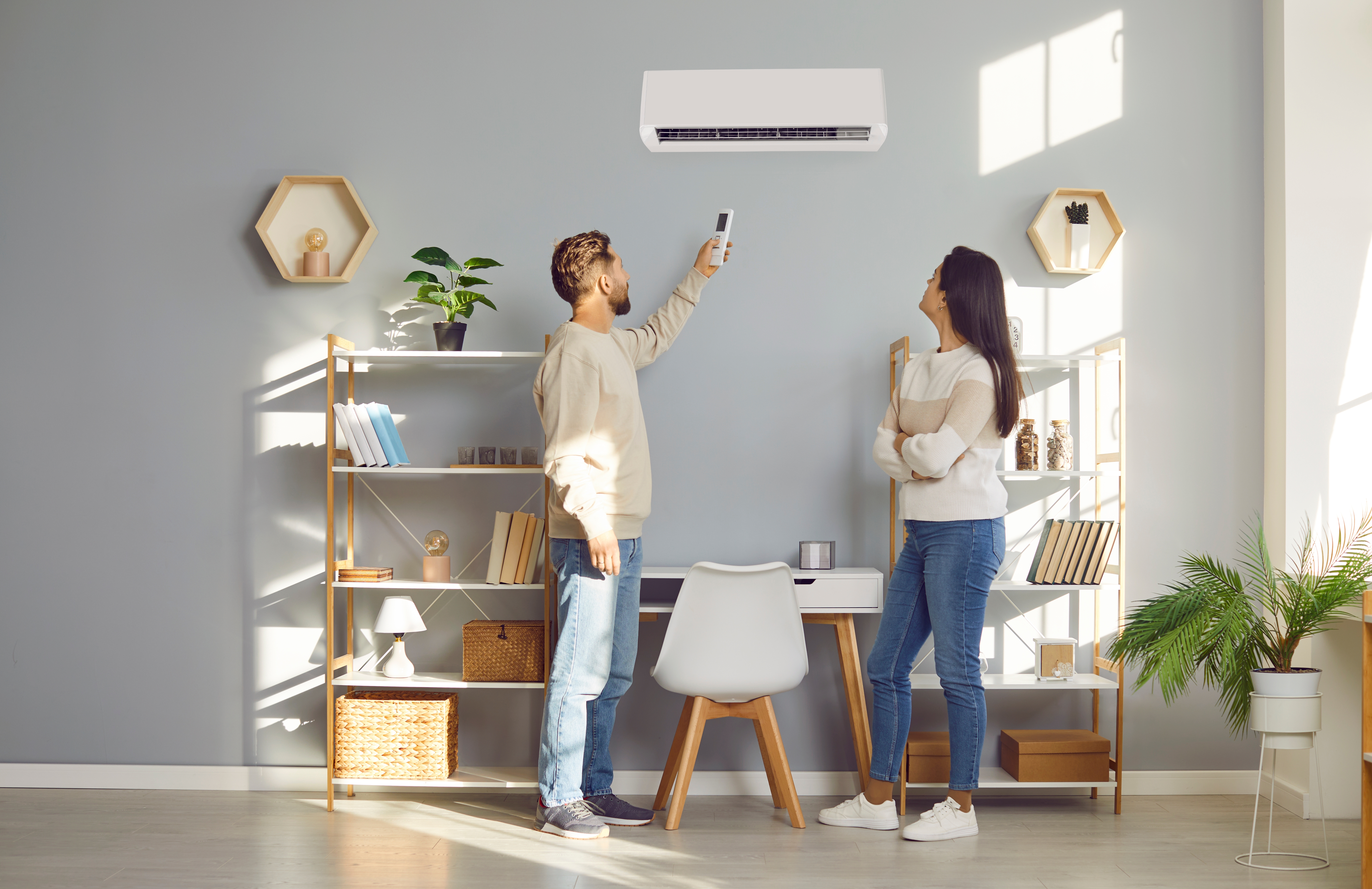 Paar steht vor Klimaanlage im Wohnzimmer 