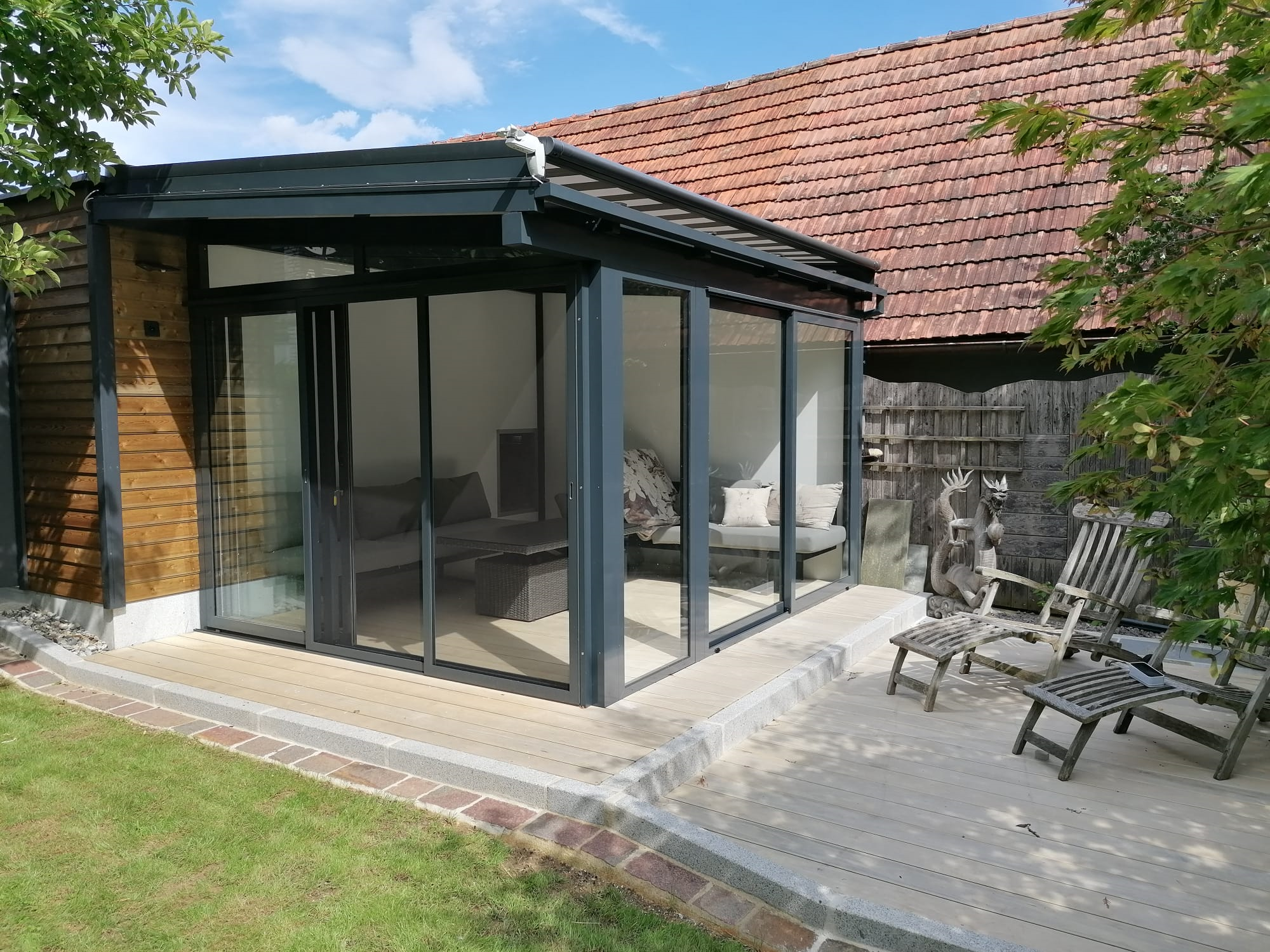 Gemütlicher Sommergarten mit Glasschiebetüren und einer Überdachmarkise