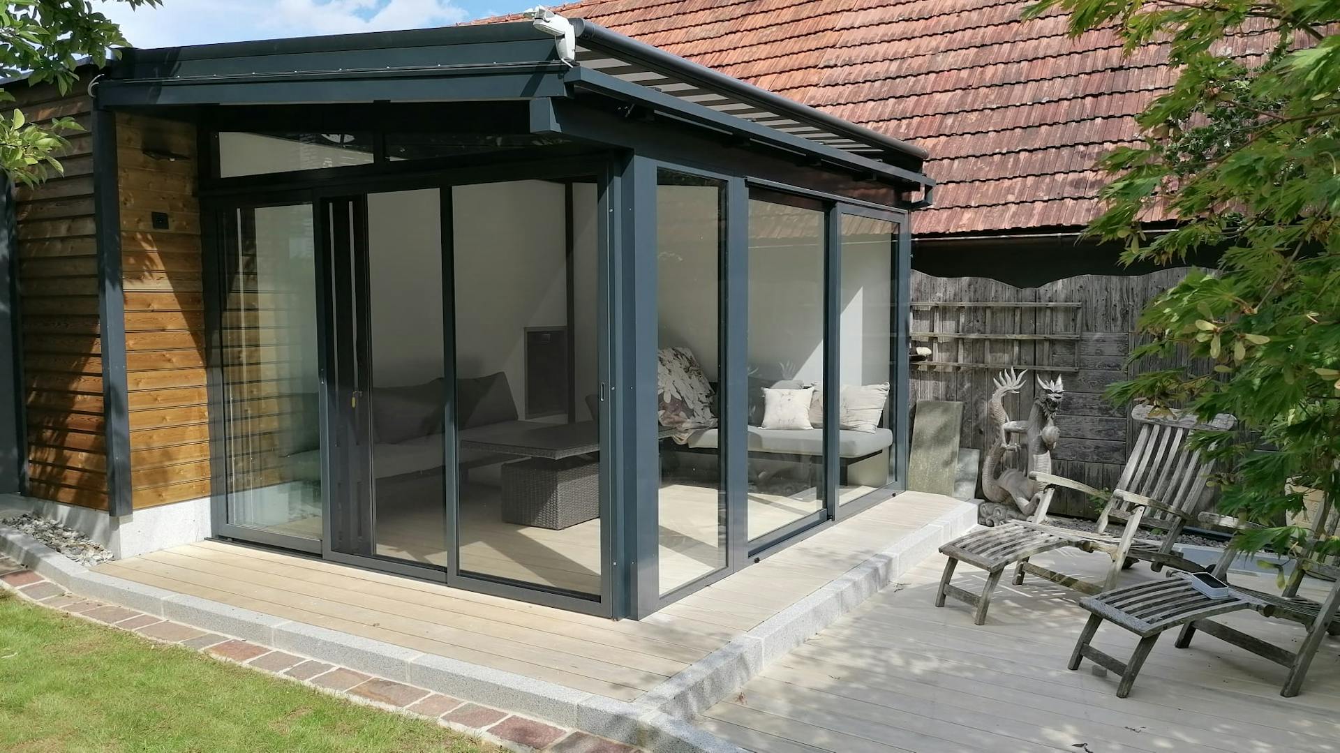 Gemütlicher Sommergarten mit Glasschiebetüren und einer Überdachmarkise