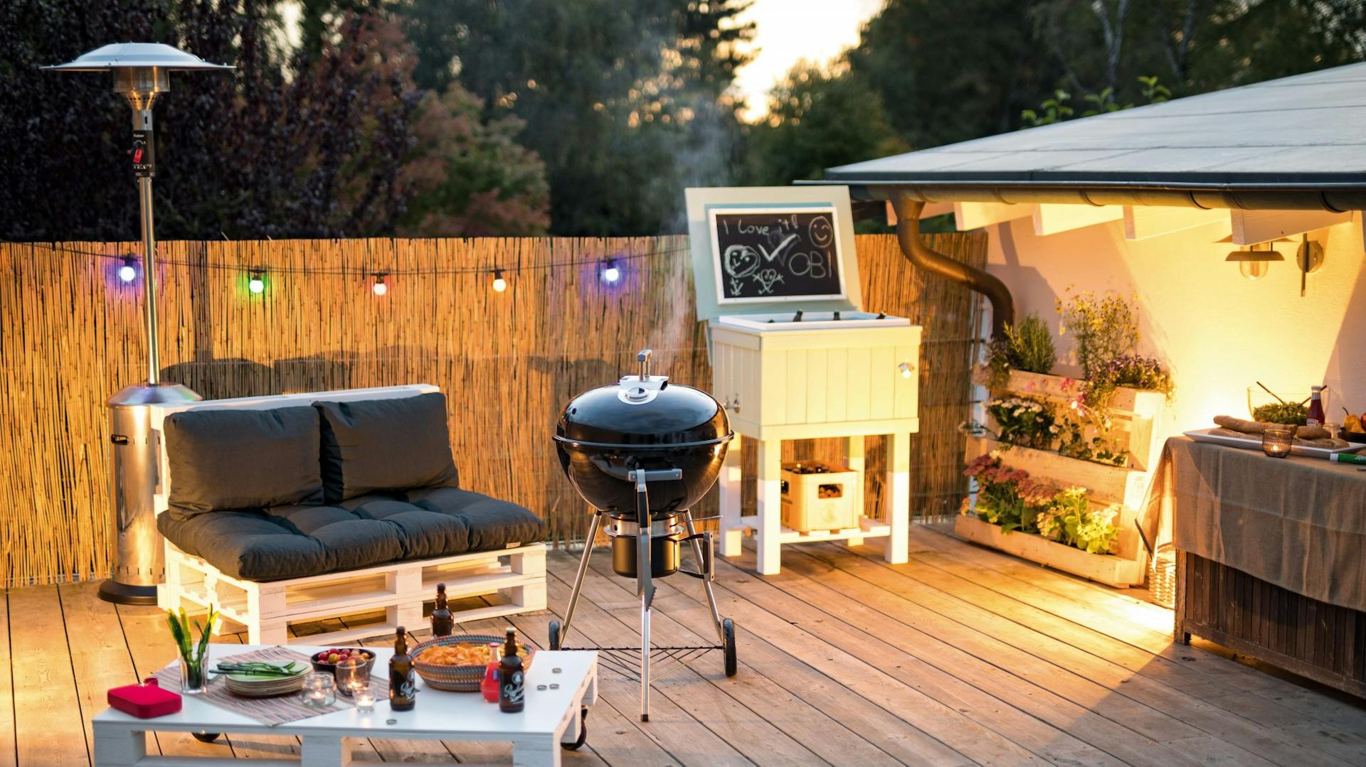 Dekorierte Grillstelle auf Balkon mit Sichtschutz und Beleuchtung