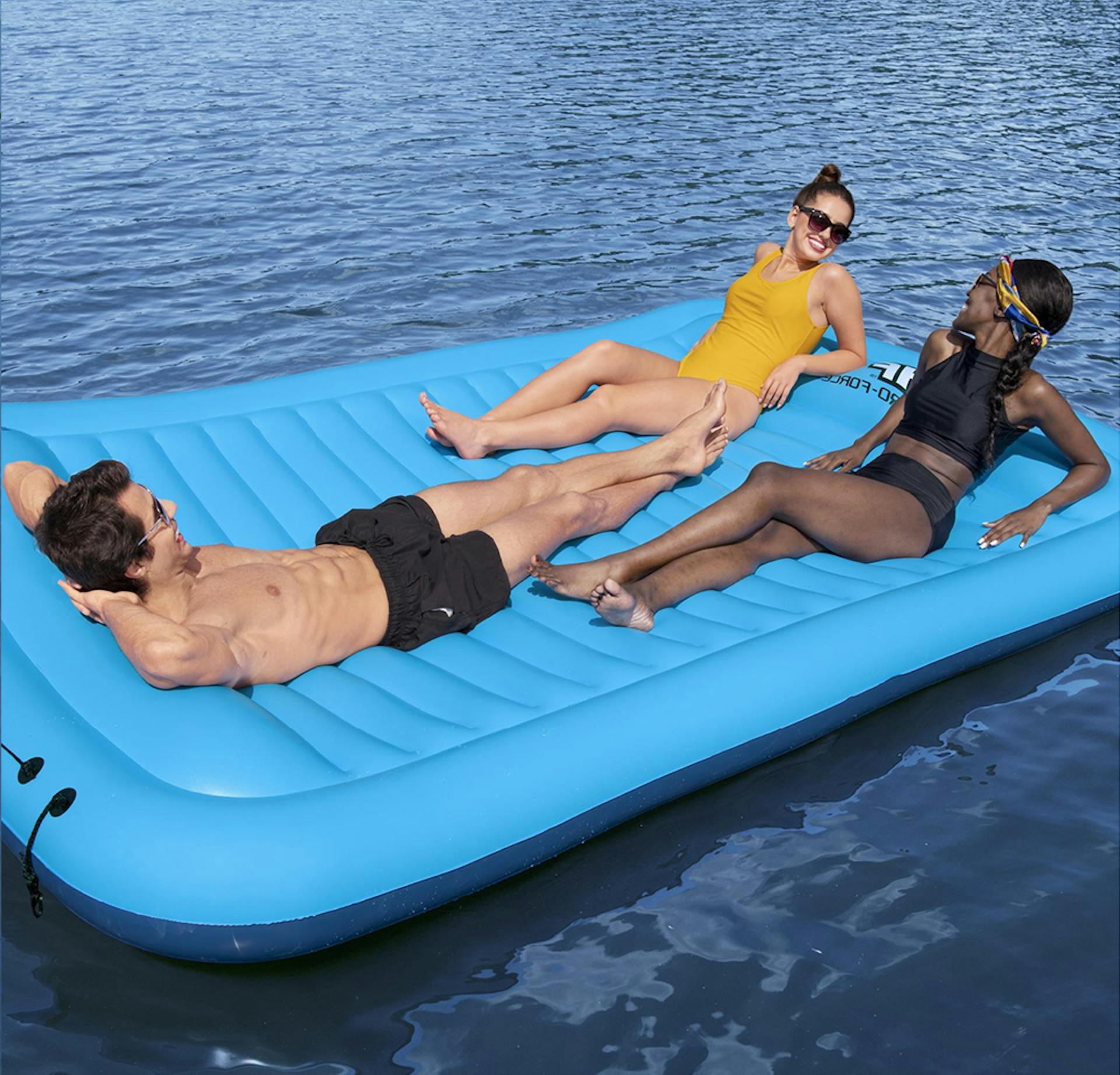 Drei Personen liegen auf einer Luftmatratze im Wasser
