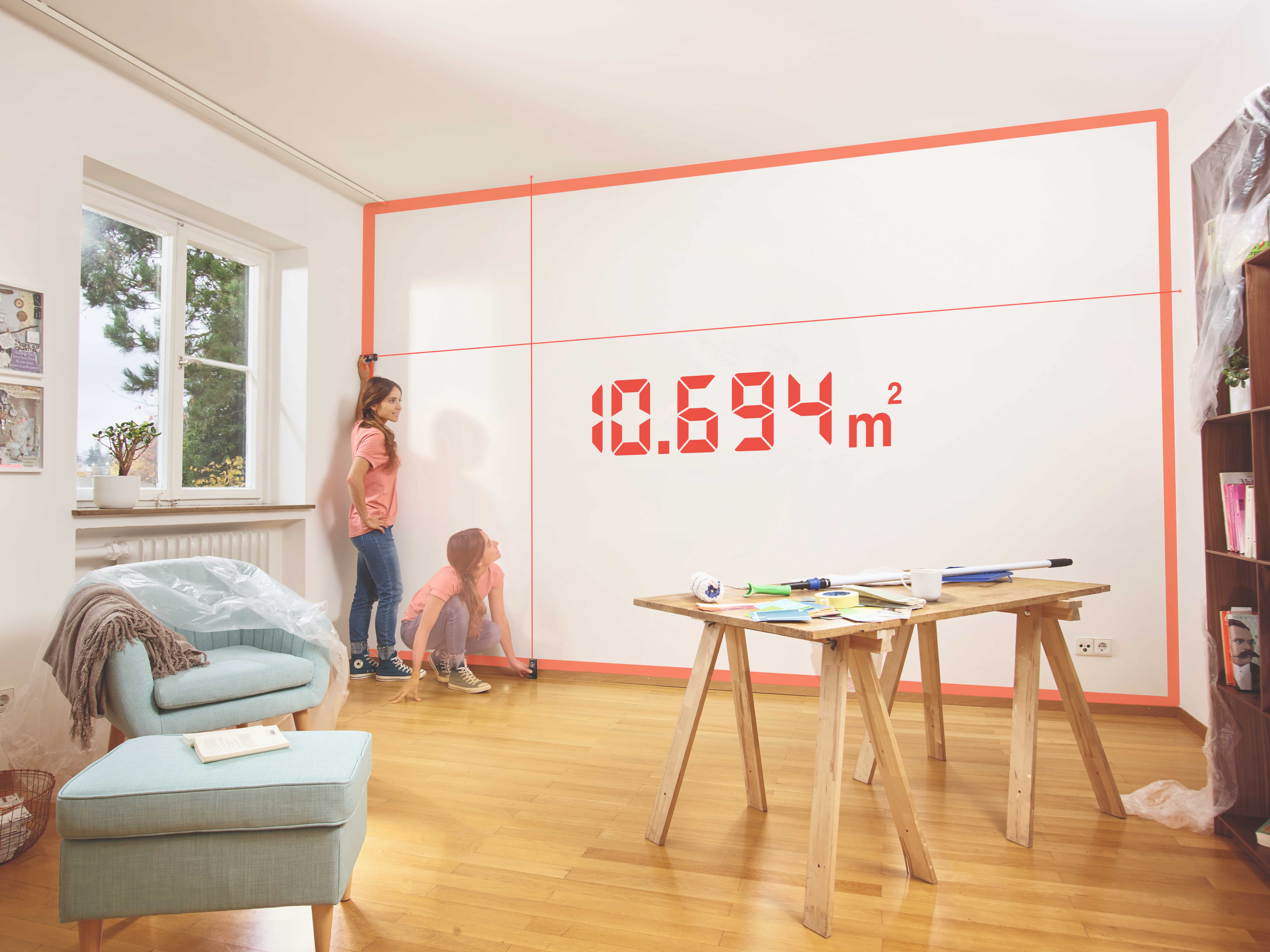 Zwei Kinder messen mit einem Bosch Messgerät eine Zimmerwand aus