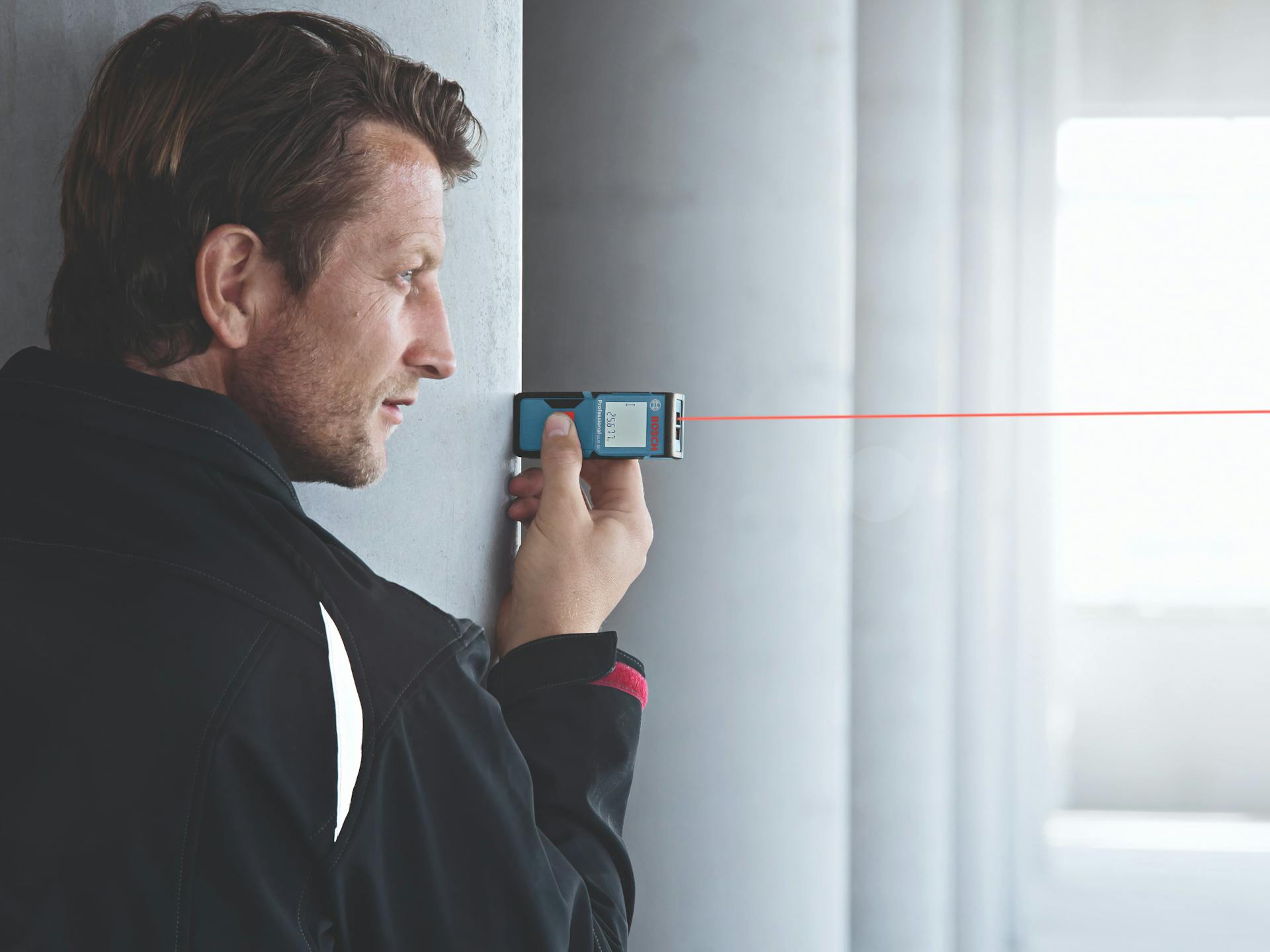 Ein Mann misst mit einem Bosch Professional Messgerät