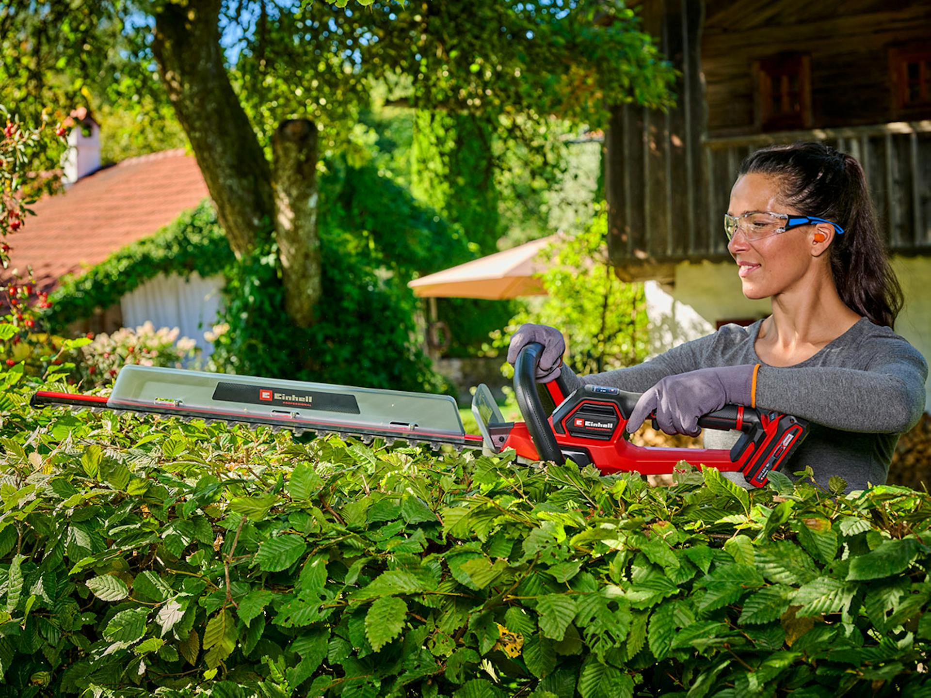 Frau schneidet Hecke mit Einhell Heckenschere