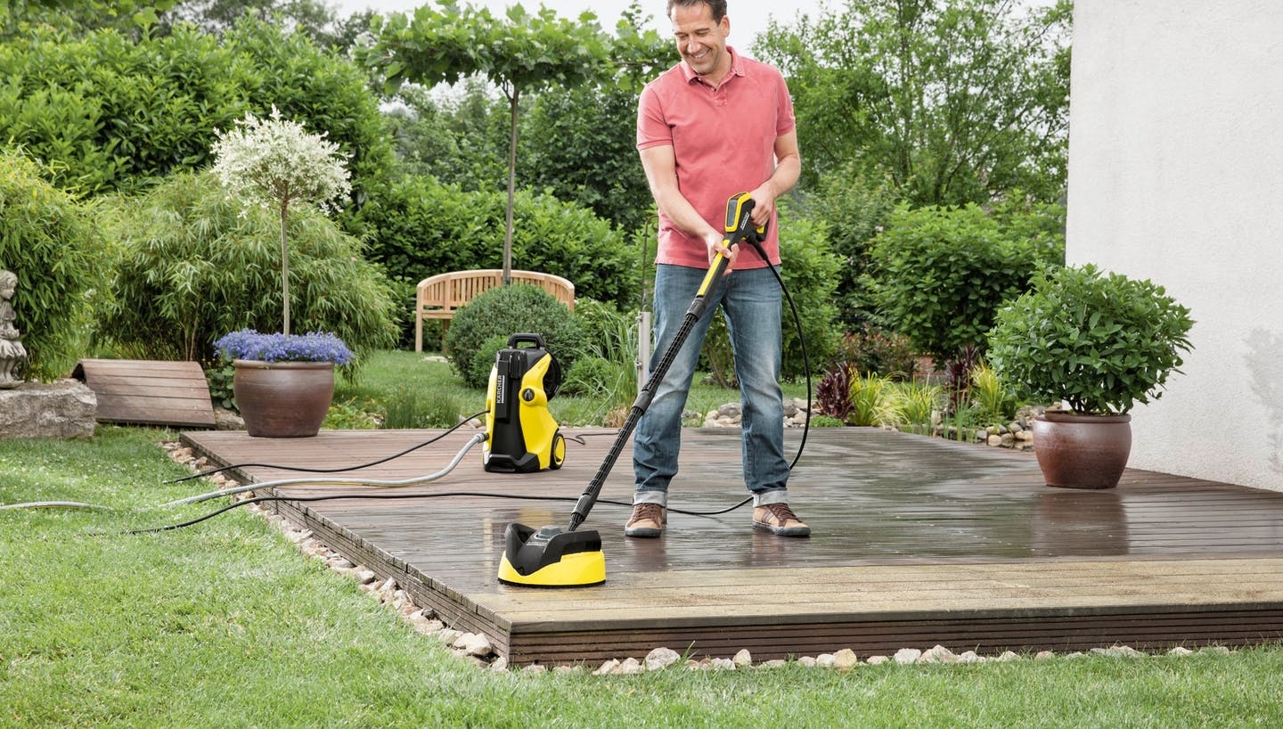 Mann reinigt Holzterrasse mit einem Kärcher Hochdruckreiniger
