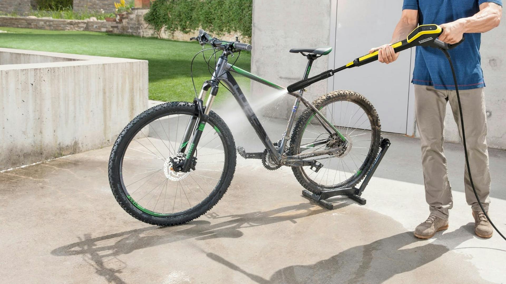 Mann reinigt Fahrrad mit einem Kärcher Hochdruckreiniger