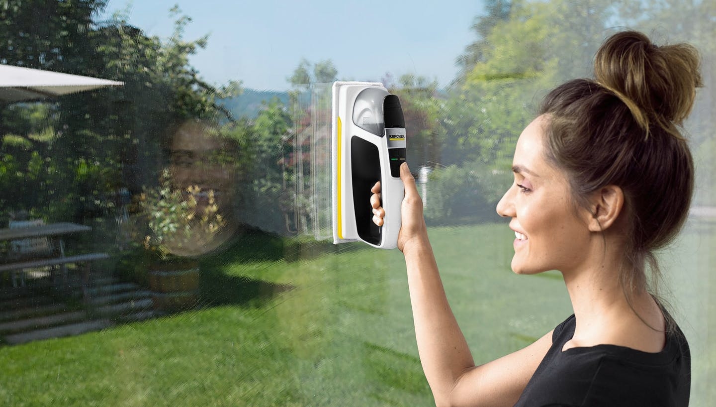 Frau reinigt Fenster mit einem Kärcher Fensterreiniger