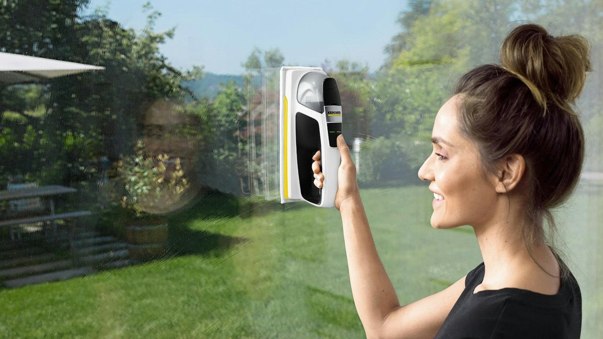 Frau reinigt Fenster mit einem Kärcher Fensterreiniger