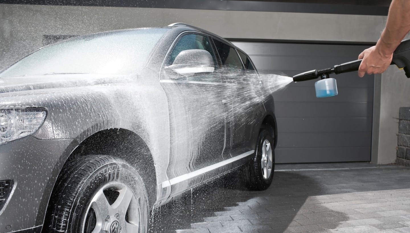 Mann reinigt Auto mit einem Kärcher Hochdruckreiniger