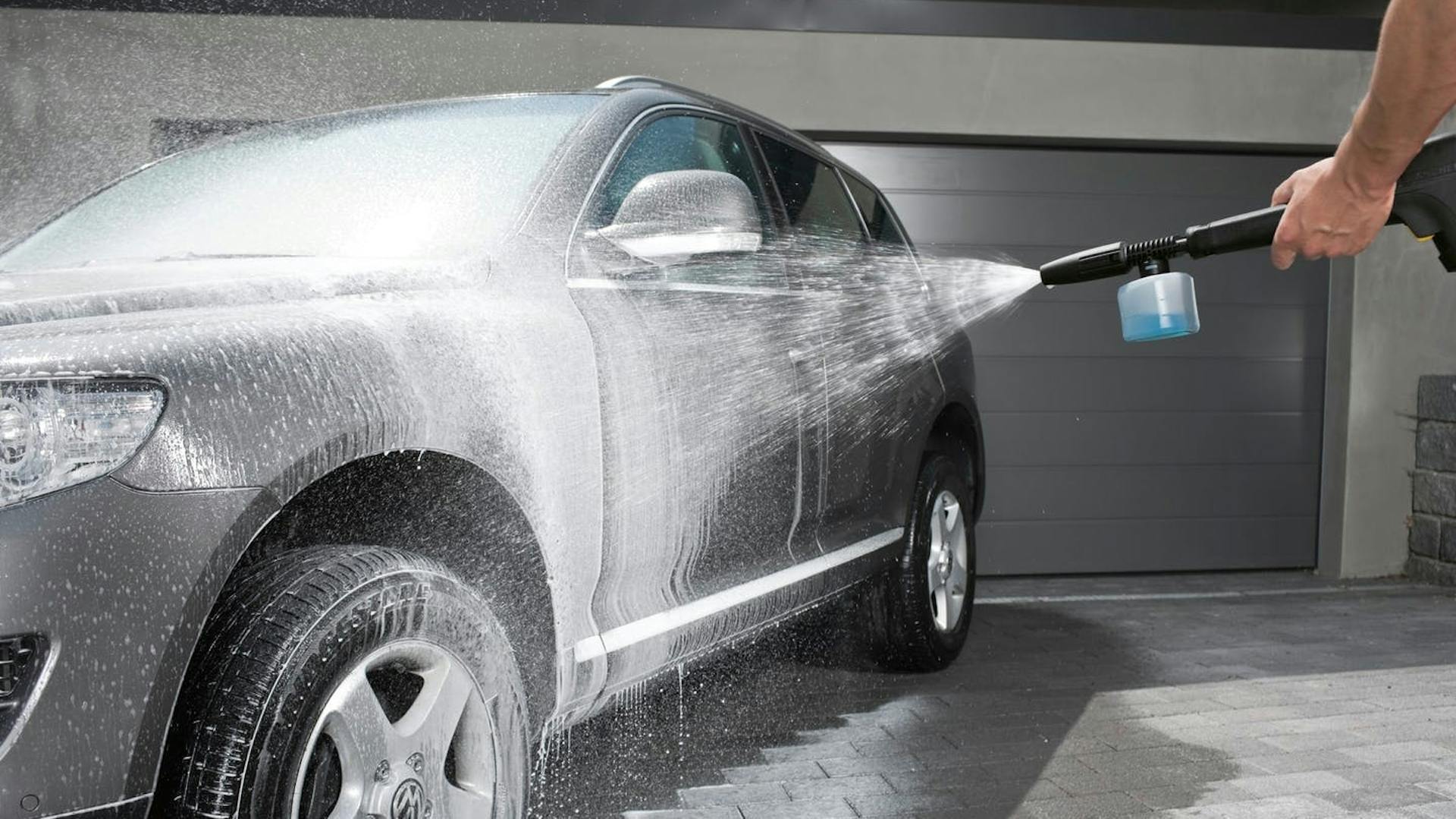 Mann reinigt Auto mit einem Kärcher Hochdruckreiniger