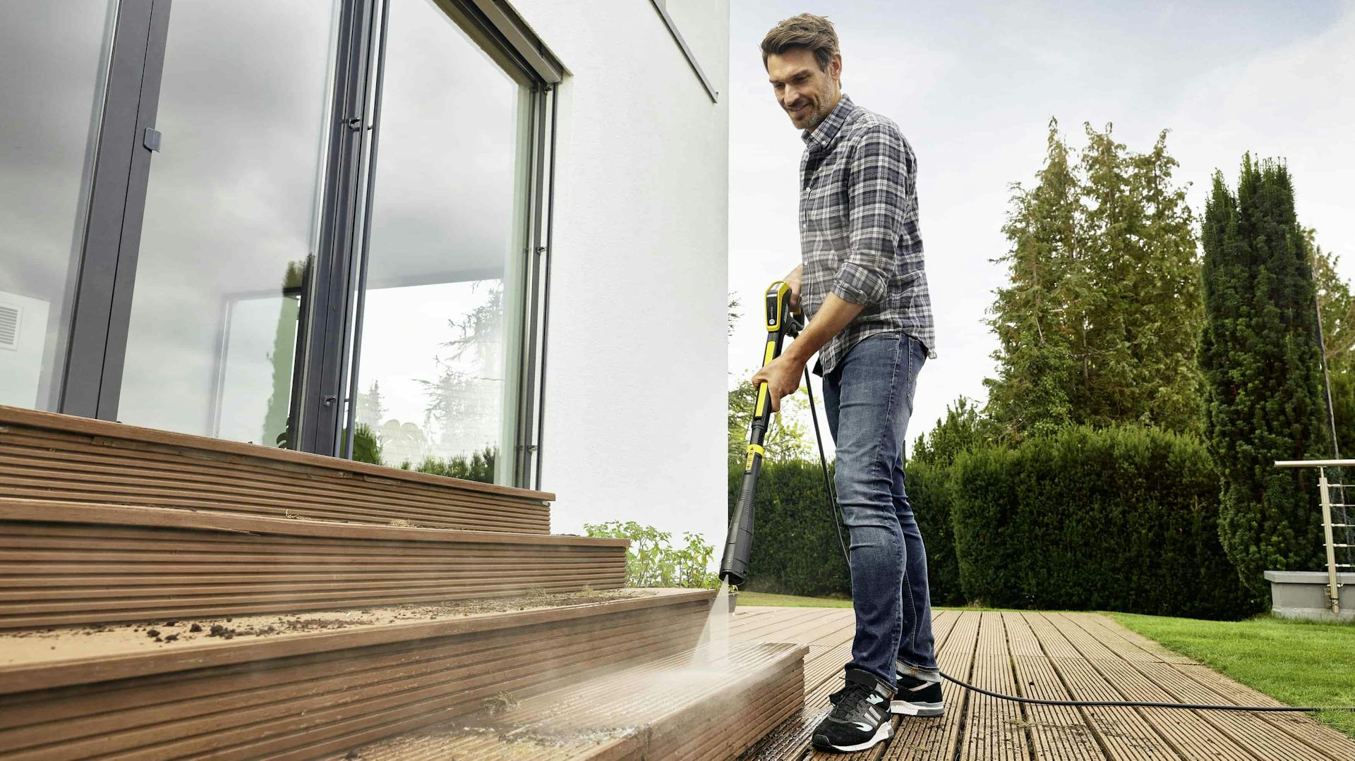 Kärcher Mann reinigt Terrassendielen mit einem Kärcher Hochdruckreiniger nutzen zum Reinigen der Terrasse