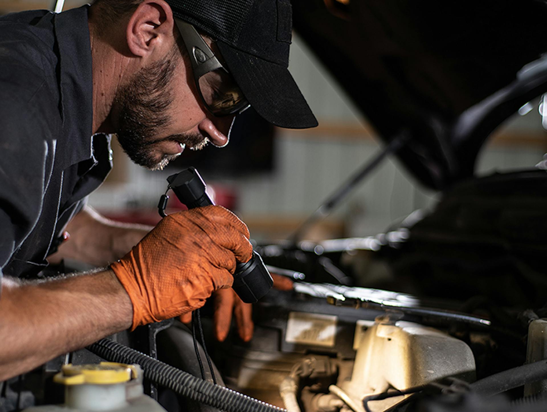 Ein Mann leuchtet mit einer Ledlenser Taschenlampe in ein Auto