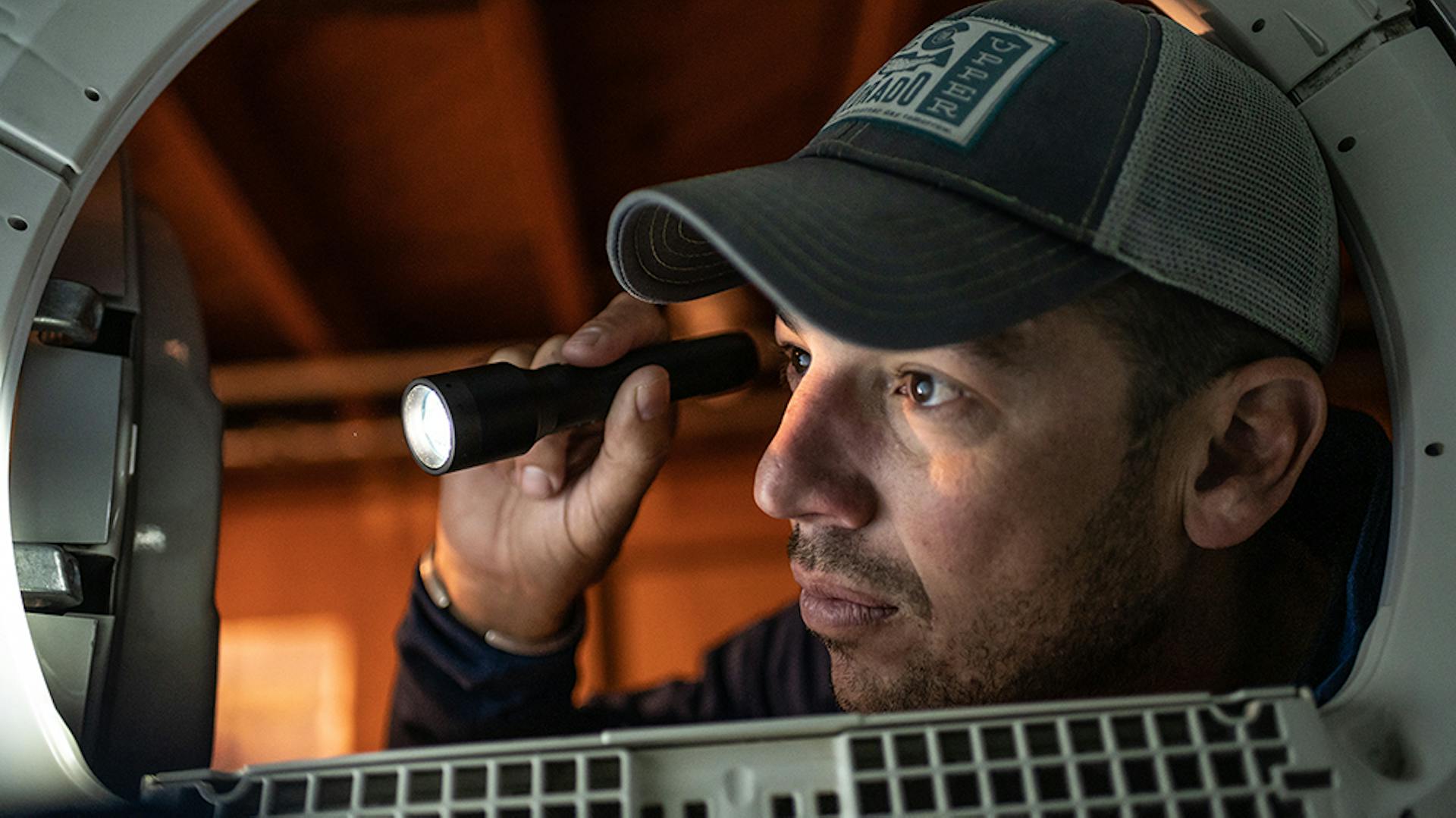 Ein Mann nutzt eine Ledlenser Taschenlampe in der Werkstatt