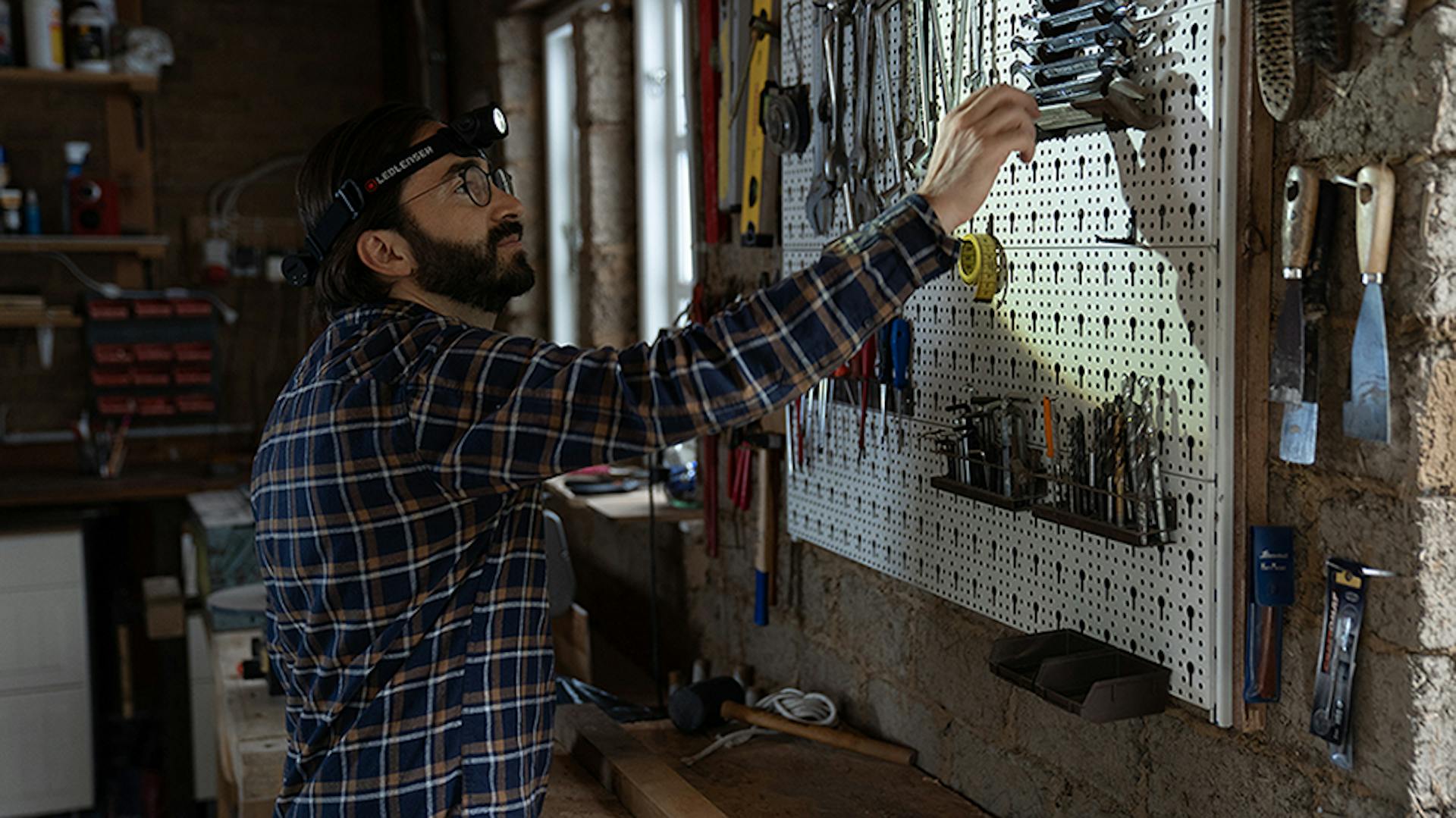 Ein Mann nutzt eine Ledlenser Stirnlampe in der Werkstatt