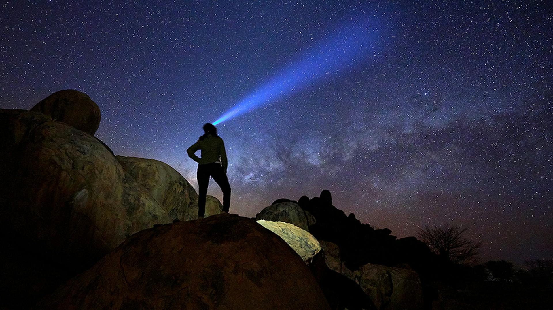 Eine Person leuchtet mit einer Ledlenser Taschenlampe in den Himmel
