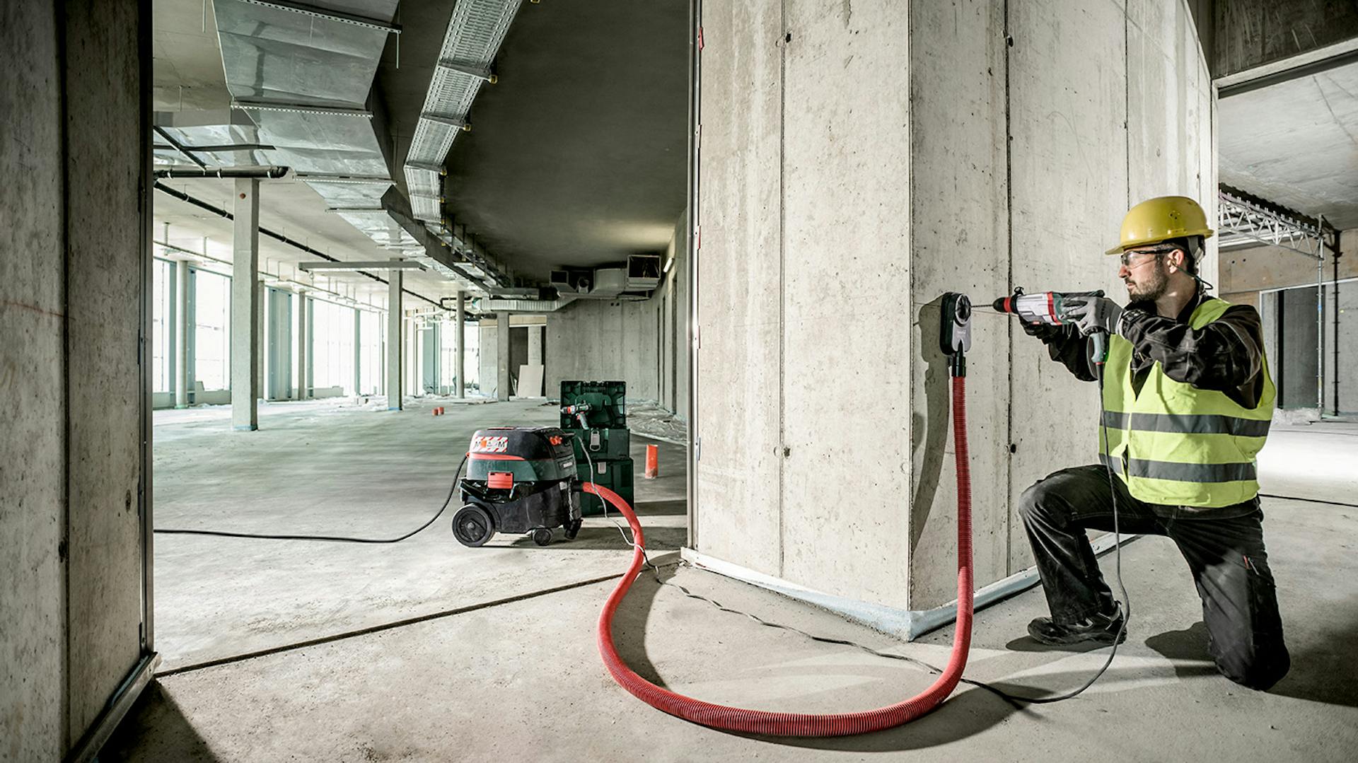 Mann bohrt auf einer Baustelle mit einem Metabo Bohrer in die Wand