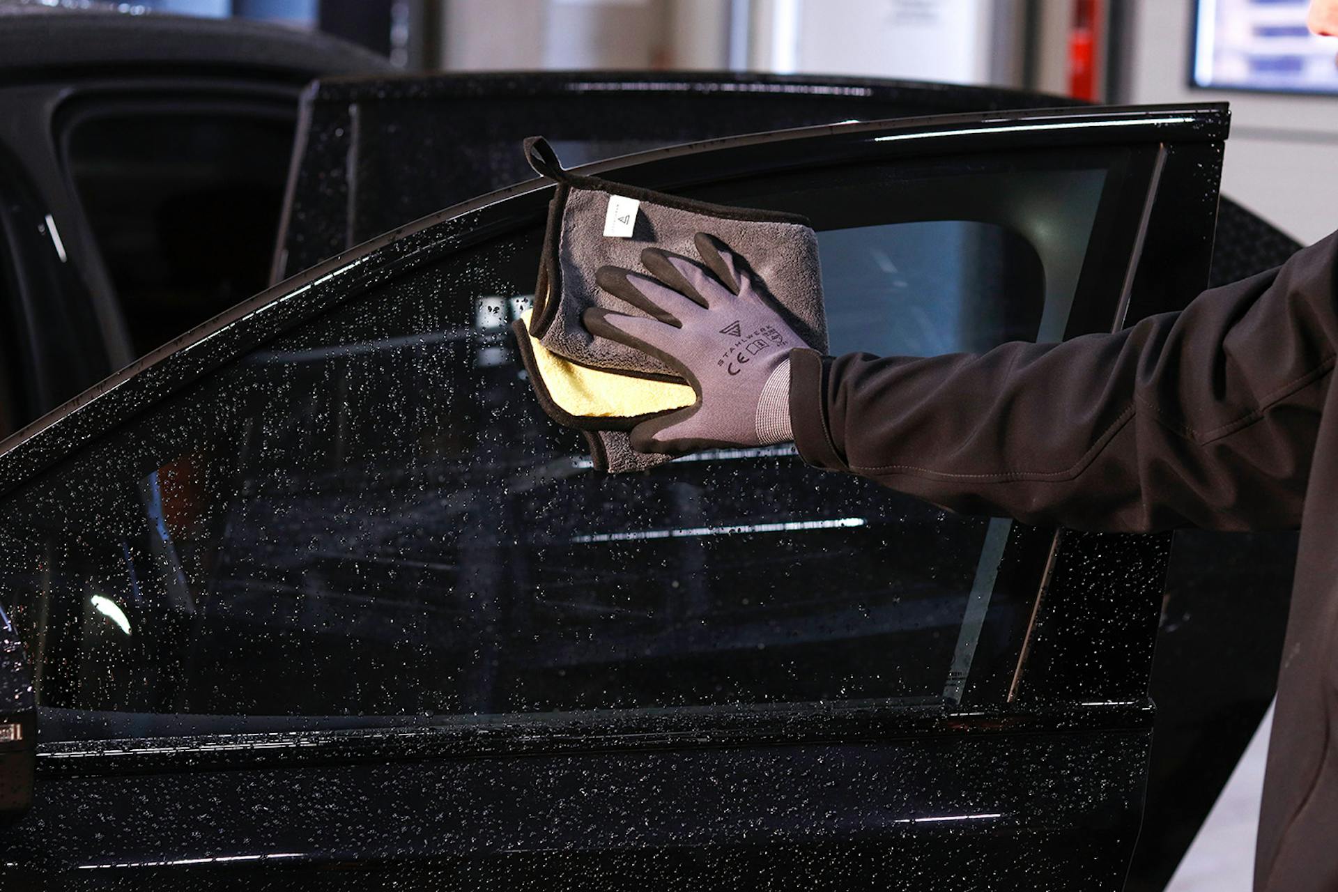 Ein Autofenster wird mit einem Stahlwerk Lappen geputzt
