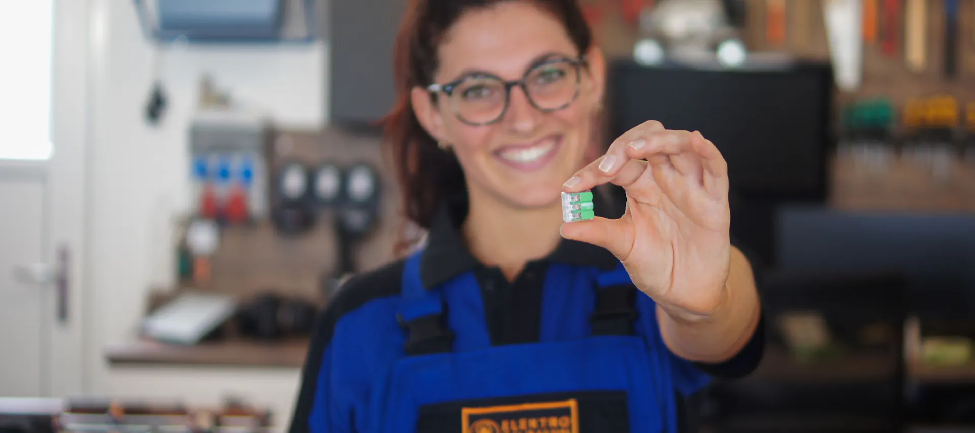 Elektrikerin mit grüner WAGO-Klemme in der Hand