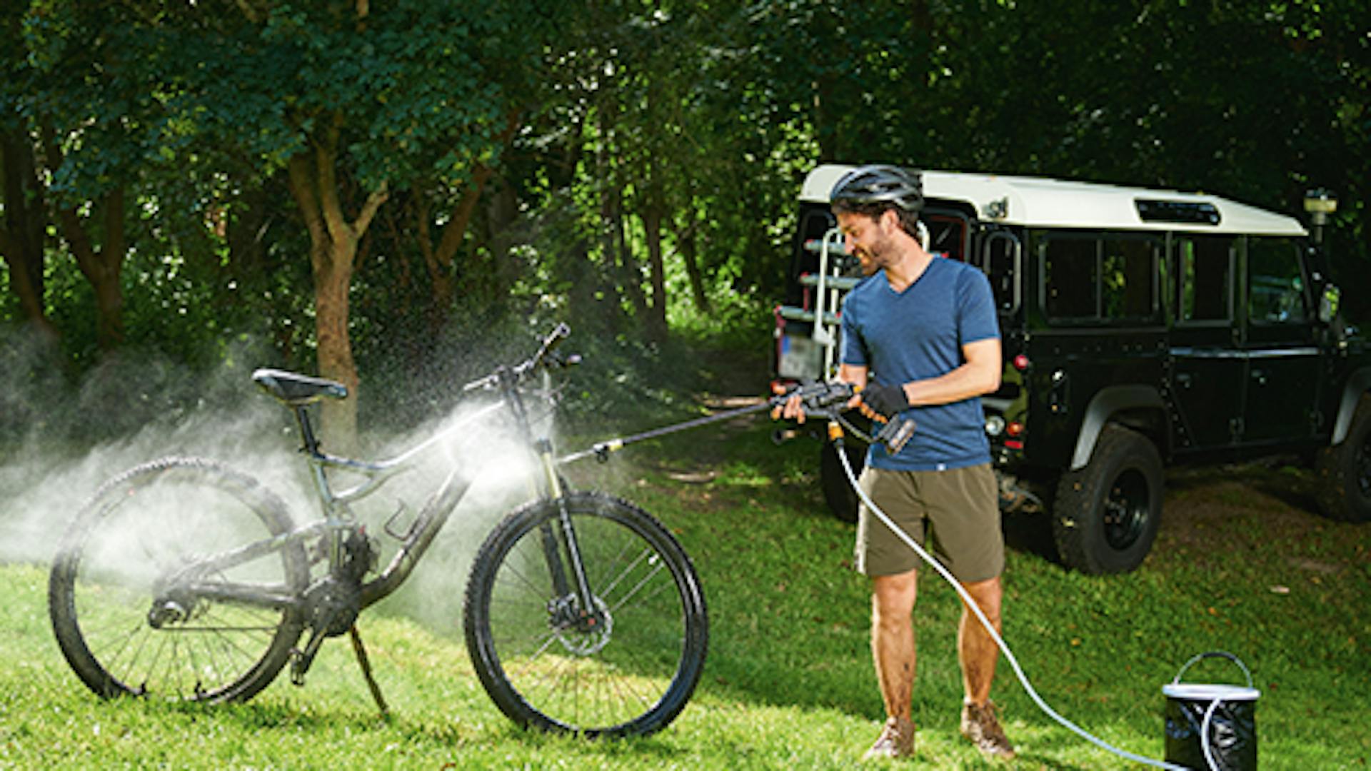 Mann Reinigt Fahrrad mit Hochdruckreiniger