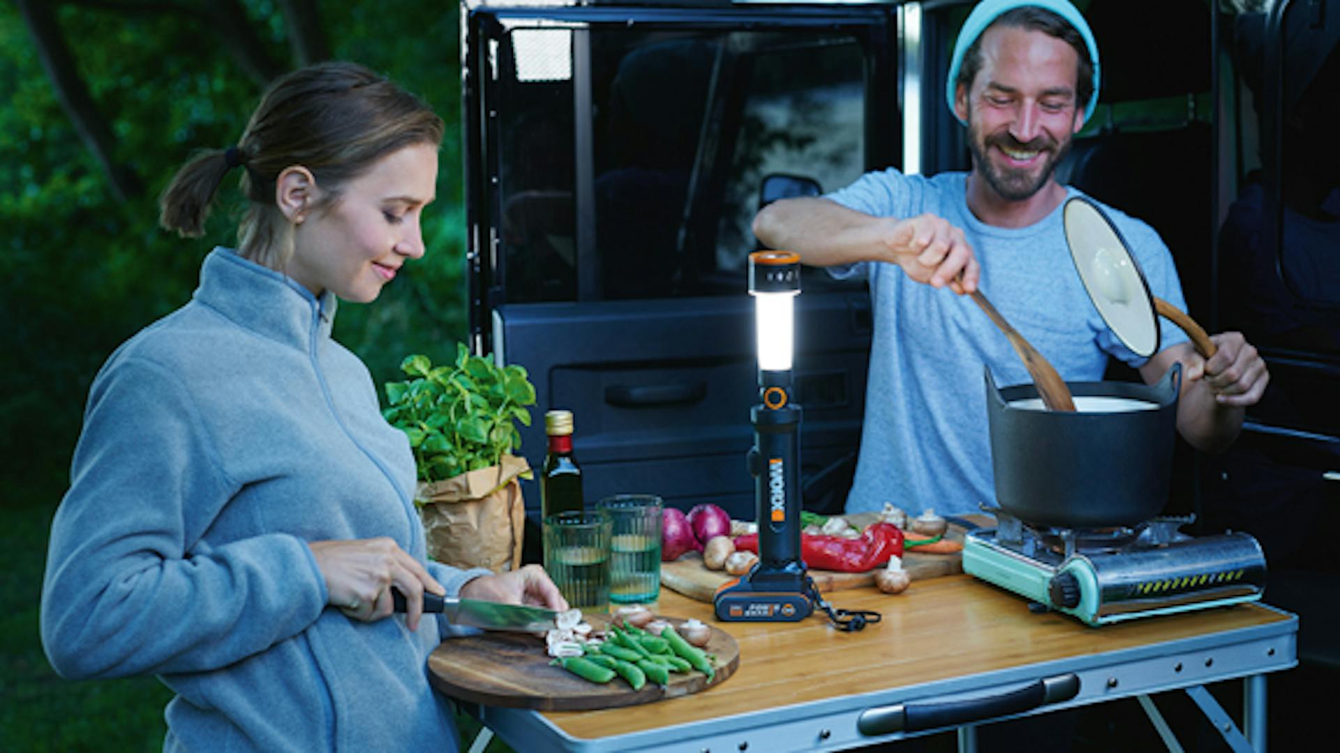 Ein Paar kocht beim Camping mit Worx Akku Lampe